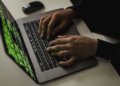Crop cyber spy hacking system while typing on laptop